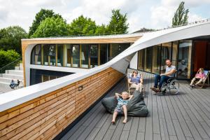 eine Gruppe von Personen, die auf dem Deck eines Gebäudes sitzen in der Unterkunft Jugendherberge Bayreuth in Bayreuth