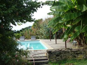 a swimming pool in a garden with two chairs next to it at La vignolle in Saint-Amand-de-Coly