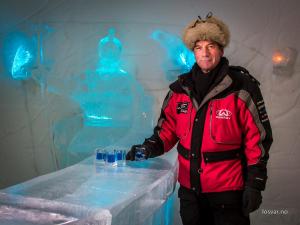 a man standing in front of a table with glasses at Sorrisniva Igloo Hotel in Alta