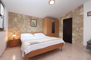 sypialnia z dużym łóżkiem i kamienną ścianą w obiekcie Apartments Marlina w Rovinj