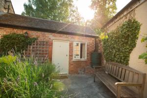 a brick building with a white door and a bench at The Talbot Inn in Cirencester