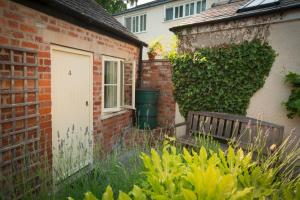 uma casa de tijolos com uma porta branca e um banco em The Talbot Inn em Cirencester