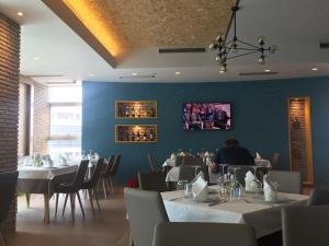 uma sala de jantar com mesas e cadeiras e uma pessoa sentada à mesa em Herges Hotel em Durrës