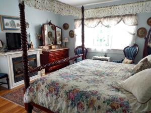 1 dormitorio con cama con dosel y chimenea en Armistead Cottage Bed & Breakfast, en Newport