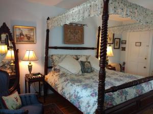 a bedroom with a canopy bed and a chair at Armistead Cottage Bed & Breakfast in Newport