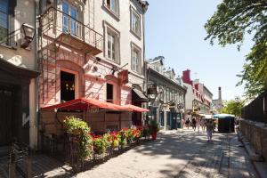 a street with a building and flowers on the sidewalk at Auberge Place d'Armes in Quebec City