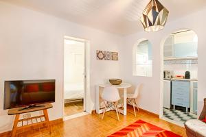 Una sala de estar con un televisor y una mesa con sillas. en BmyGuest - Mouraria Central Apartment II, en Lisboa 8 fotos más