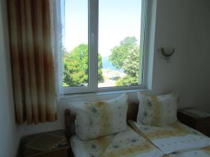a bedroom with a window and a bed with pillows at Sunhouse Rooms in Tsarevo