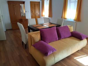 a living room with a couch and a table with purple pillows at Apartman Kaszás Central in Mosonmagyaróvár