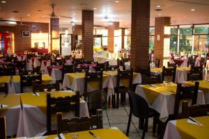 a restaurant with tables and chairs with yellow and white table cloth at Hotel El Libertador in Puerto Iguazú