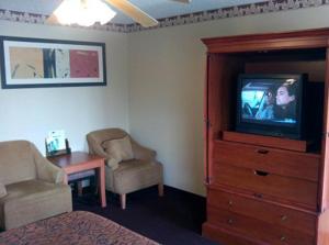Western Inn Hamilton في Hamilton: غرفة نوم مع تلفزيون وكرسي ومكتب