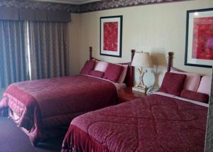 a hotel room with two beds with red sheets at Western Inn Hamilton in Hamilton