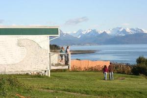 um grupo de pessoas de pé em uma varanda com vista para a água em Ocean Shores Hotel em Homer