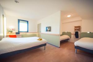 um quarto de hotel com duas camas e uma janela em ibis budget Troyes Est em Saint-Parres-aux-Tertres