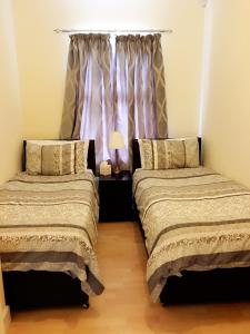 two beds in a room with white sheets and pillows at Acer Lodge Guest House in Edinburgh