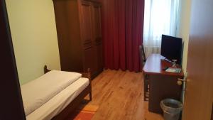 1 dormitorio con cama, escritorio y cortina roja en Hotel Mare & Monti, en Bassersdorf