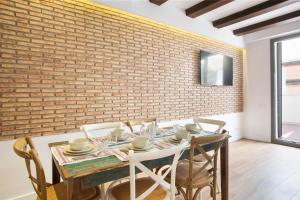 comedor con pared de ladrillo, mesa y sillas en Sweet Home Sitges BY BLAUSITGES, en Sitges