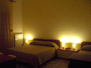 a bedroom with two beds and two lights on the wall at Etna Inn in Motta SantʼAnastasia