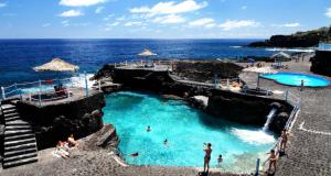 a pool on the beach with people in the water at La Casa del Abuelo in Los Sauces
