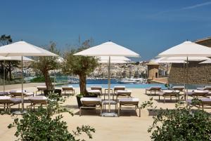 
a beach area with tables, chairs and umbrellas at The Phoenicia Malta in Valletta
