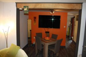 a dining room with an orange wall and a table and chairs at Lesse matinal in Redu