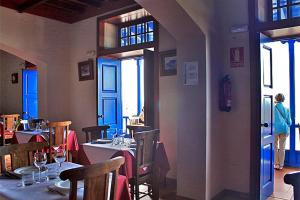 a restaurant with tables and chairs and a person standing in the doorway at La Casa del Abuelo in Los Sauces