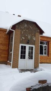 a house with a white door in the snow at Holiday Home Rayskiy Ugolochek in Kvitki