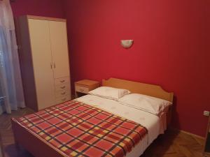 a bedroom with a bed and a red wall at Apartman Vito in Medulin