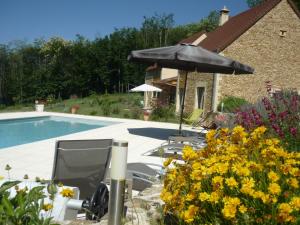 a pool with chairs and an umbrella and flowers at Les Deux Moiselles - Le Cheyssignaguet in La Chapelle-Aubareil