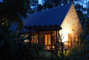 a small stone house with a lit up facade at night at Witches Falls Cottages in Mount Tamborine