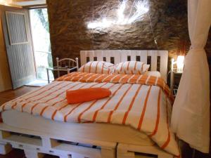 a bedroom with a bed with a white and orange comforter at Watermill Moinho Garcia in Pinheiro da Bemposta