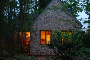 a small stone house with lights in the window at Witches Falls Cottages in Mount Tamborine