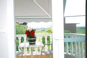 a vase with red flowers on a table on a porch at John & Eve Hotel in Paralia Katerinis