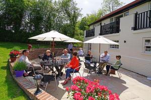 un gruppo di persone seduti ai tavoli sotto gli ombrelloni di The Greyhound Inn a Edenbridge