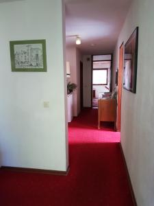 un corridoio vuoto con un tappeto rosso e una camera di Pension Streng-Reinhardt a Ostfildern