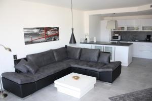 ein Wohnzimmer mit einem schwarzen Sofa und einer Küche in der Unterkunft Salvatorferienwohnung in Schwäbisch Gmünd