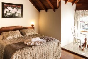 a bedroom with a bed and a table and a chair at Hotel Aconchego da Serra in Gramado