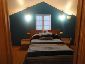 a bedroom with a bed with a blue wall at Dúplex OS BATANS in Laxe