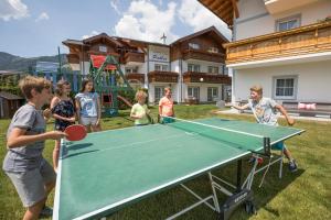 a group of children standing around a ping pong table at Aparthotel Pichler in Flachau