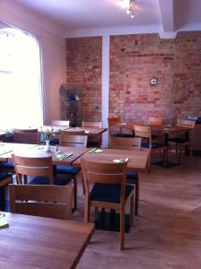 a restaurant with wooden tables and chairs and a brick wall at Kågeröds Värdshus Tre Stjärnor in Kågeröd +9 photos