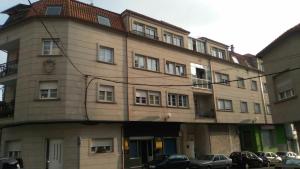 a large building with cars parked in front of it at Apartamento La Basella in Villanueva de Arosa