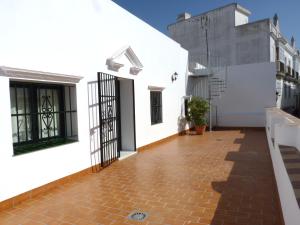 a balcony of a house with white walls and a brick floor at Hostal Boutique Casa La Laja in Chiclana de la Frontera