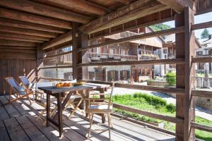 une terrasse en bois avec une table et des chaises. dans l'établissement Albergo Diffuso Sauris in Sauris Di Sopra, à Sauris