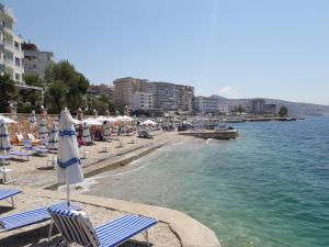 a beach with chairs and an umbrella and the water at Olive Tree Apartment in Sarandë