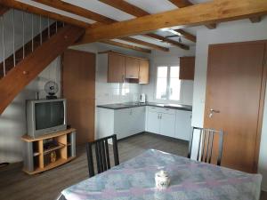 eine Küche und ein Esszimmer mit einem Tisch und einem TV in der Unterkunft Gîte Découverte Alsace in Kuhlendorf