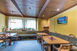 a restaurant with wooden ceilings and tables and chairs at Pension Bäuerle in Heiligenblut