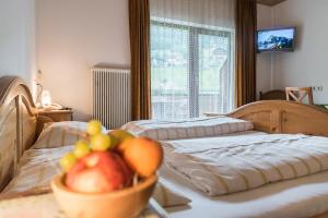 sypialnia z 2 łóżkami i miską owoców na stole w obiekcie Pension Bäuerle w mieście Heiligenblut