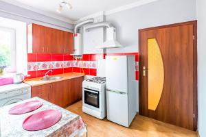 Il comprend une cuisine dotée de murs rouges et d'un réfrigérateur blanc. dans l'établissement Rainbow apartment near Rynok sq, à Lviv