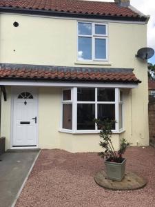 a white house with a white door and a plant at Wolds Cottage Pocklington in Pocklington