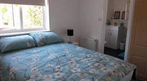 a bedroom with a bed with a blue comforter and a window at Wolds Cottage Pocklington in Pocklington